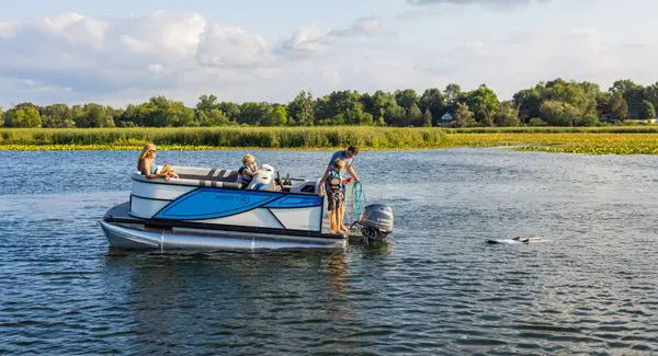 A man throwing out rope so his son can wakeboard behind a Godfrey Mighty G pontoon boat.