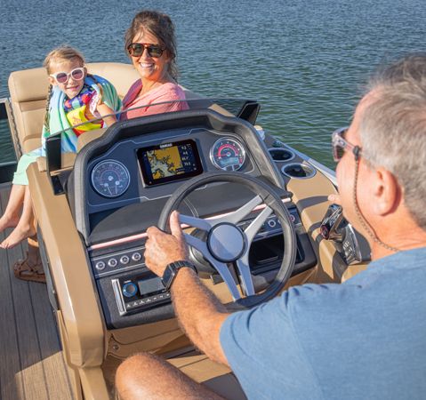 Man sitting at the elevated helm of a Godfrey Monaco pontoon boat.