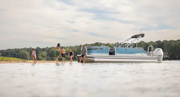 5 people on shore near a Godfrey Monaco pontoon boat.