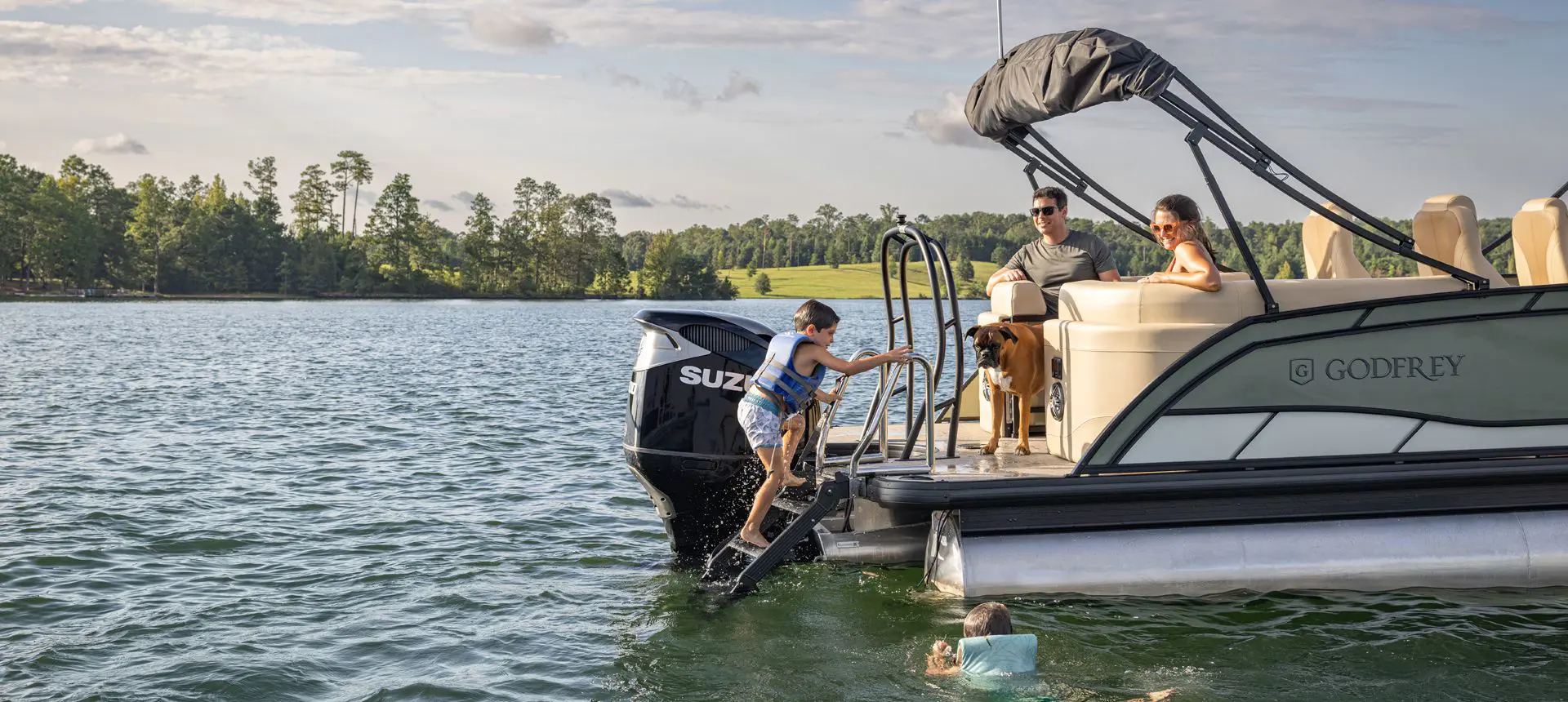 A kid climbing up the stern ladder on a Godfrey Monaco pontoon boat.