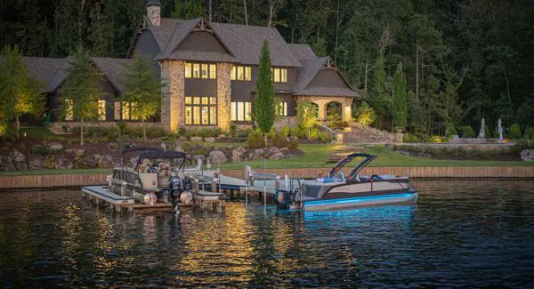 A Godfrey Monaco pontoon boat with RGB full-spectrum lighting docked near shore.