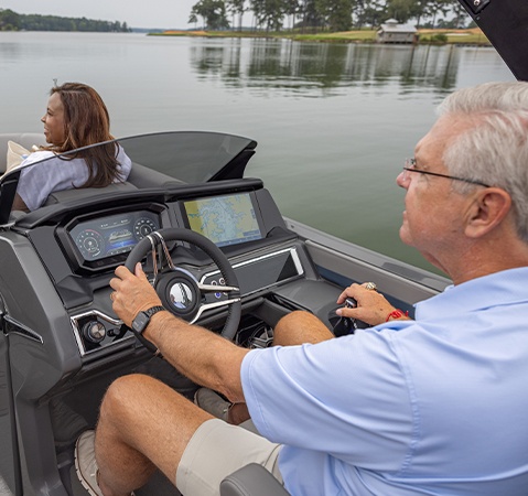 A man sitting at the intuitive helm of a Godfrey Sanpan pontoon boat featuring a 12-inch display.