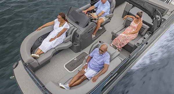 4 people relaxing on a Godfrey Sanpan pontoon boat while cruising a lake.