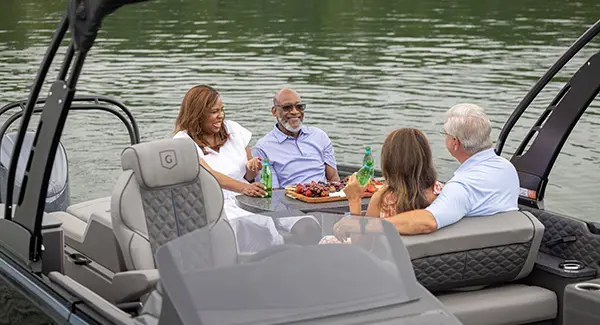 4 people enjoying a meal at the stern table on a Godfrey Sanpan pontoon boat.