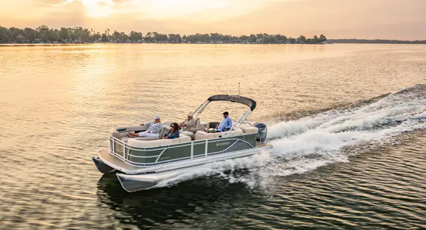 4 people cruising the lake at sunset on a Godfrey Sweetwater pontoon boat.