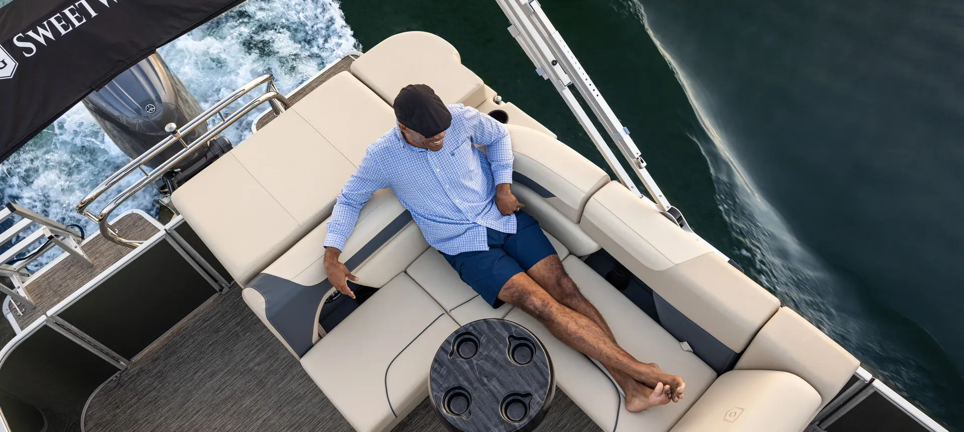 A man relaxing on the stern bench seating on a Godfrey Sweetwater pontoon boat.