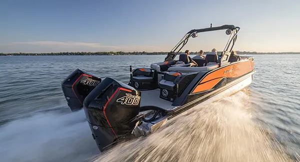 A Godfrey XP tritoon boat with twin engines speeding across a lake.