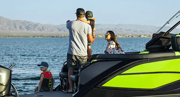 A father pointing to the horizon while holding his son on a Godfrey XP tritoon boat.