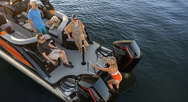 A woman climbing the stern ladder of a Godfrey XP tritoon boat after a swim.
