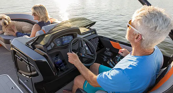 Over-the-shoulder view of a man sitting at the dual digital helm on his Godfrey XP tritoon boat.