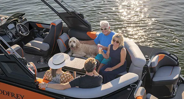 4 people and a good enjoying a beverage at the stern table on a Godfrey XP tritoon boat.