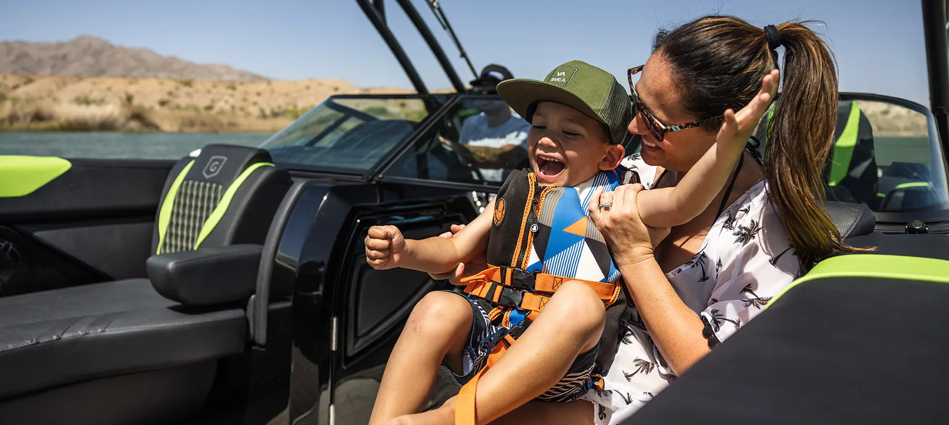 A kid in a life jacket enjoying time on the lake with his family on their Godfrey XP tritoon boat.
