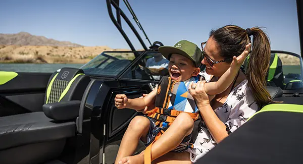 A kid in a life jacket enjoying time on the lake with his family on their Godfrey XP tritoon boat.