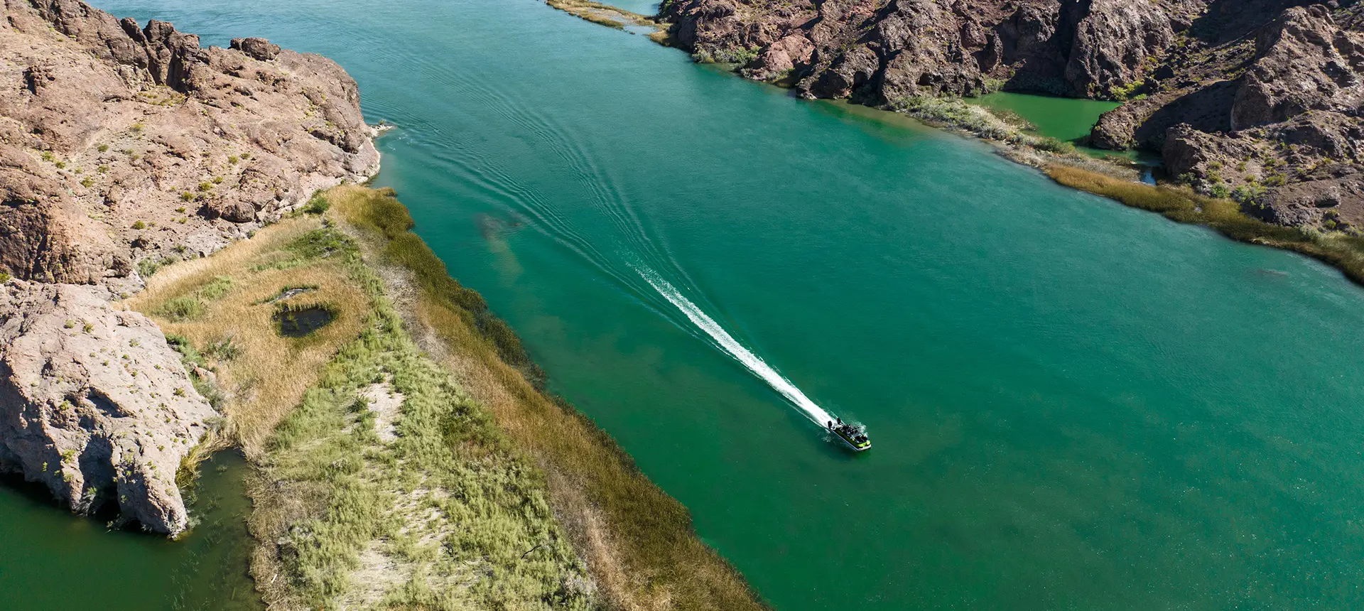 Aerial view of a Godfrey XP tritoon boat driving through a lagoon.