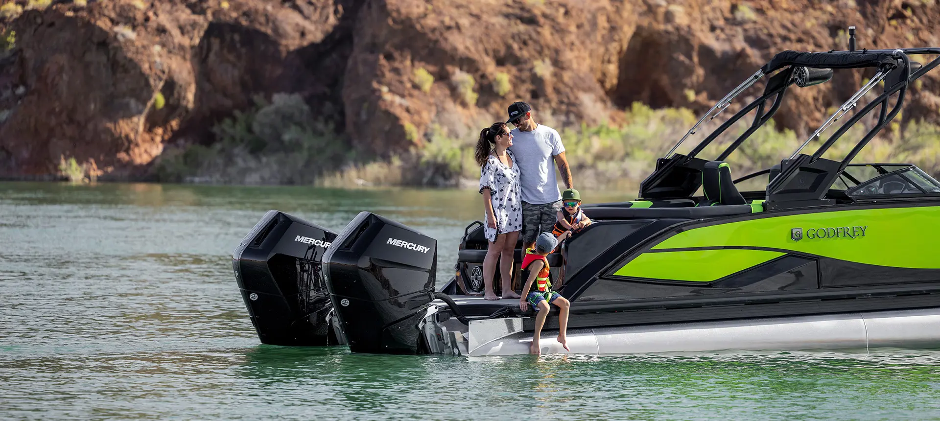 2 parents and 2 kids standing on the stern of a Godfrey XP tritoon boat.