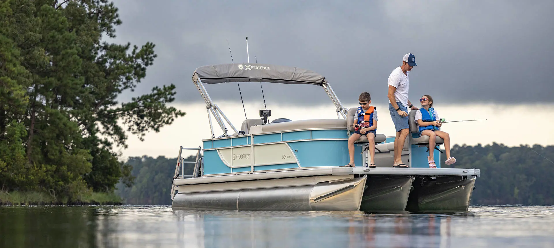 A man teaching his kids to fish off the bow of a Godfrey Xperience pontoon boat.