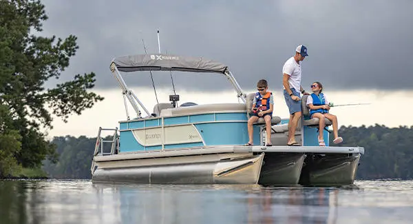 A man teaching his kids to fish off the bow of a Godfrey Xperience pontoon boat.