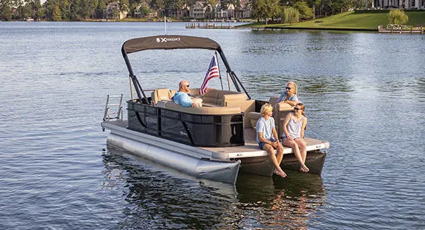 A family of four relaxing on a Godfrey Xperience tritoon boat while floating the lake.