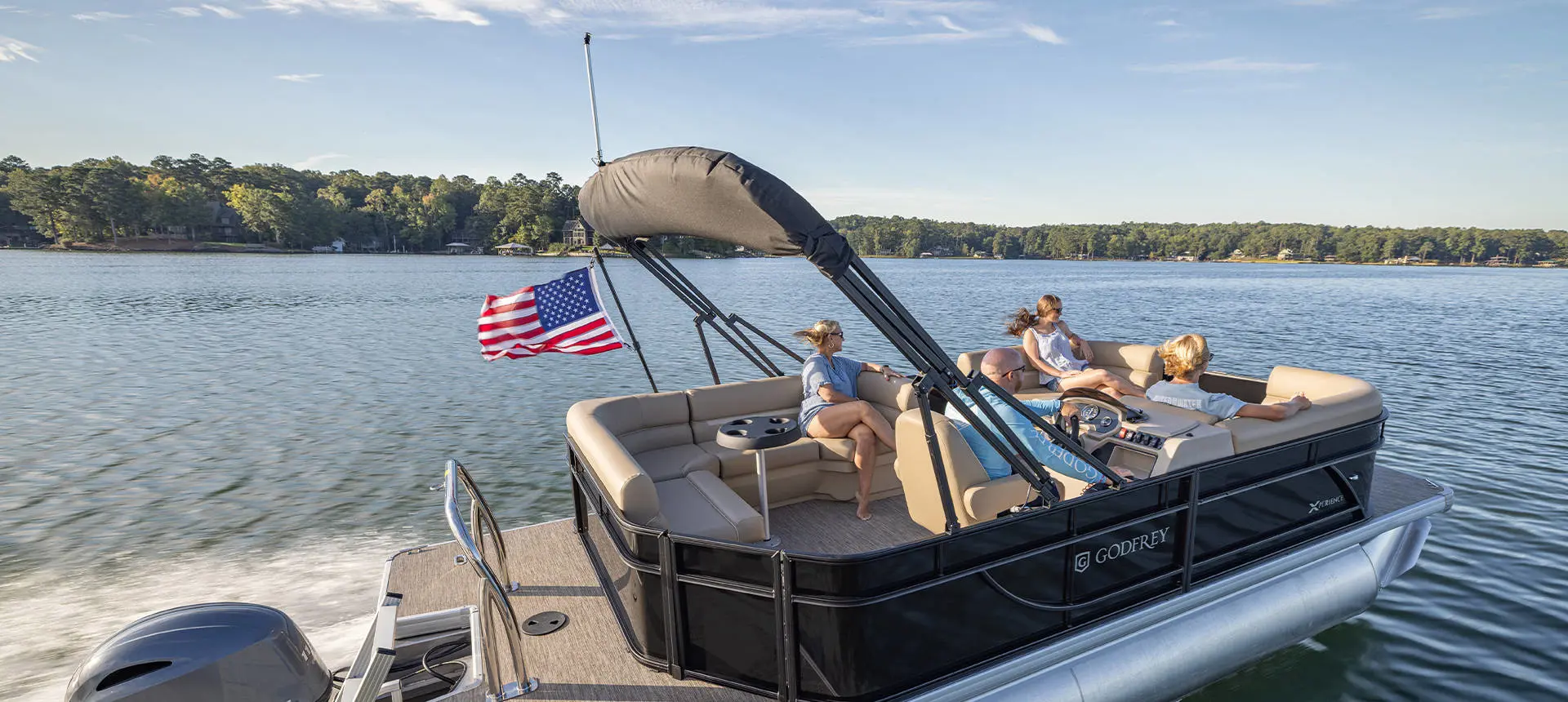 4 people cruising the lake with their Godfrey Xperience pontoon boat.