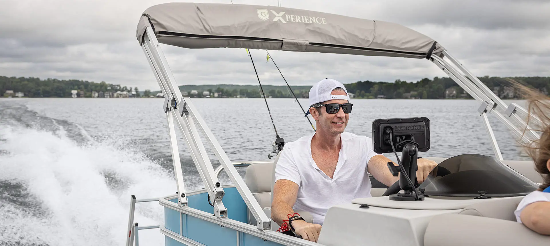 A man at the helm of a Godfrey Xperience pontoon boat.