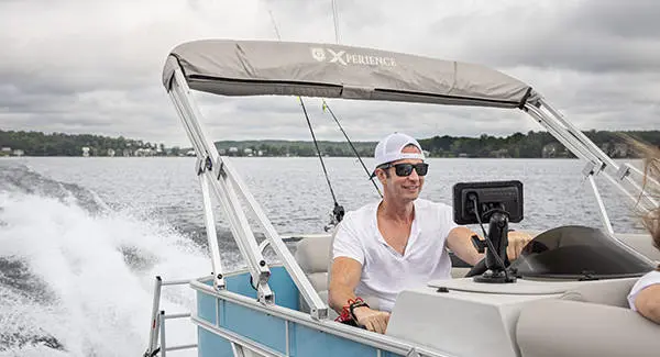 A man at the helm of a Godfrey Xperience pontoon boat.