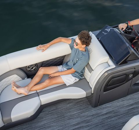 A young man sitting on the ergonomically engineers bow seating on a Godfrey pontoon boat.