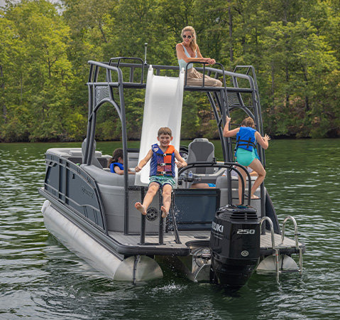 A kid sliding into the water from the SunDeck of a Godfrey pontoon boat with a SunDeck layout.