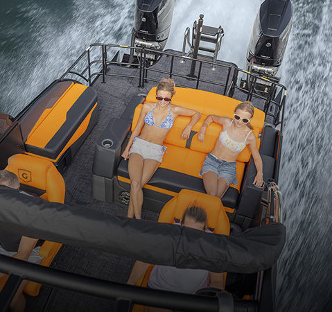 A couple sitting on the flip lounge seat on a Godfrey pontoon boat with the Single Flip Lounge Twin (SFL) layout.