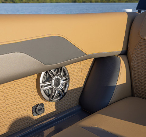 Close-up of premium upholstery and a built-in marine speaker aboard a Godfrey AquaPatio pontoon boat.