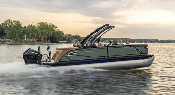 Side profile of a Godfrey AquaPatio pontoon boat cruising across a lake.