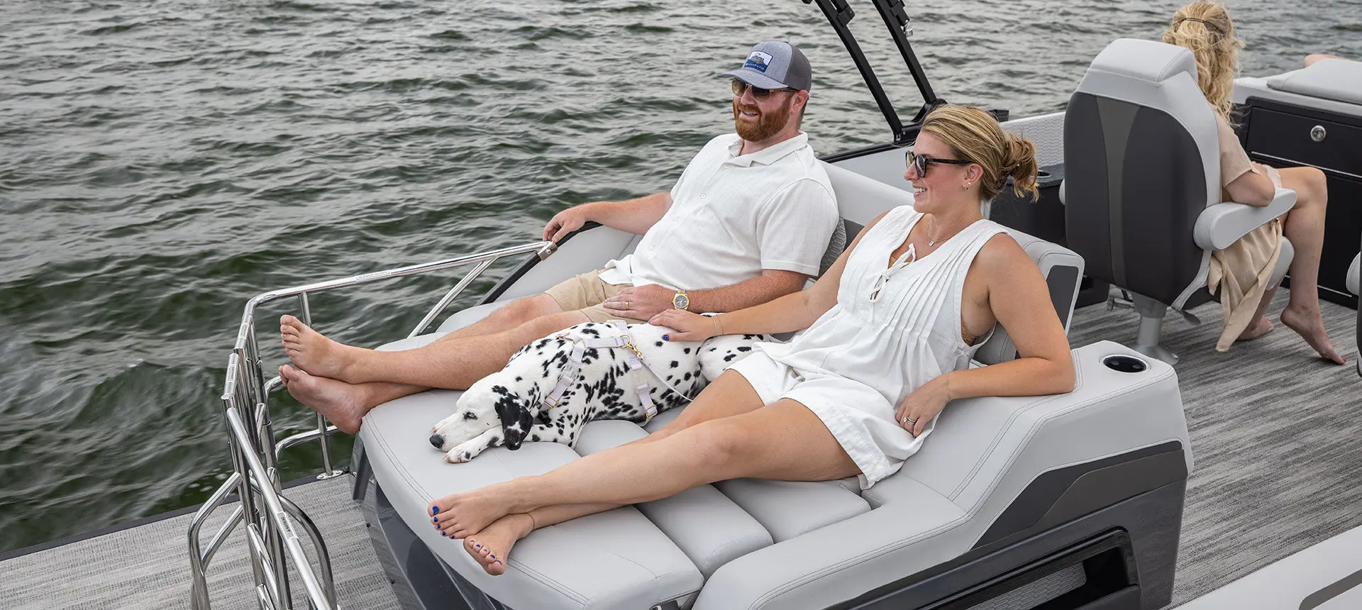 A couple relaxing on the flip lounge on a Godfrey AquaPatio pontoon boat.