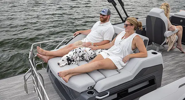 A couple relaxing on the flip lounge on a Godfrey AquaPatio pontoon boat.