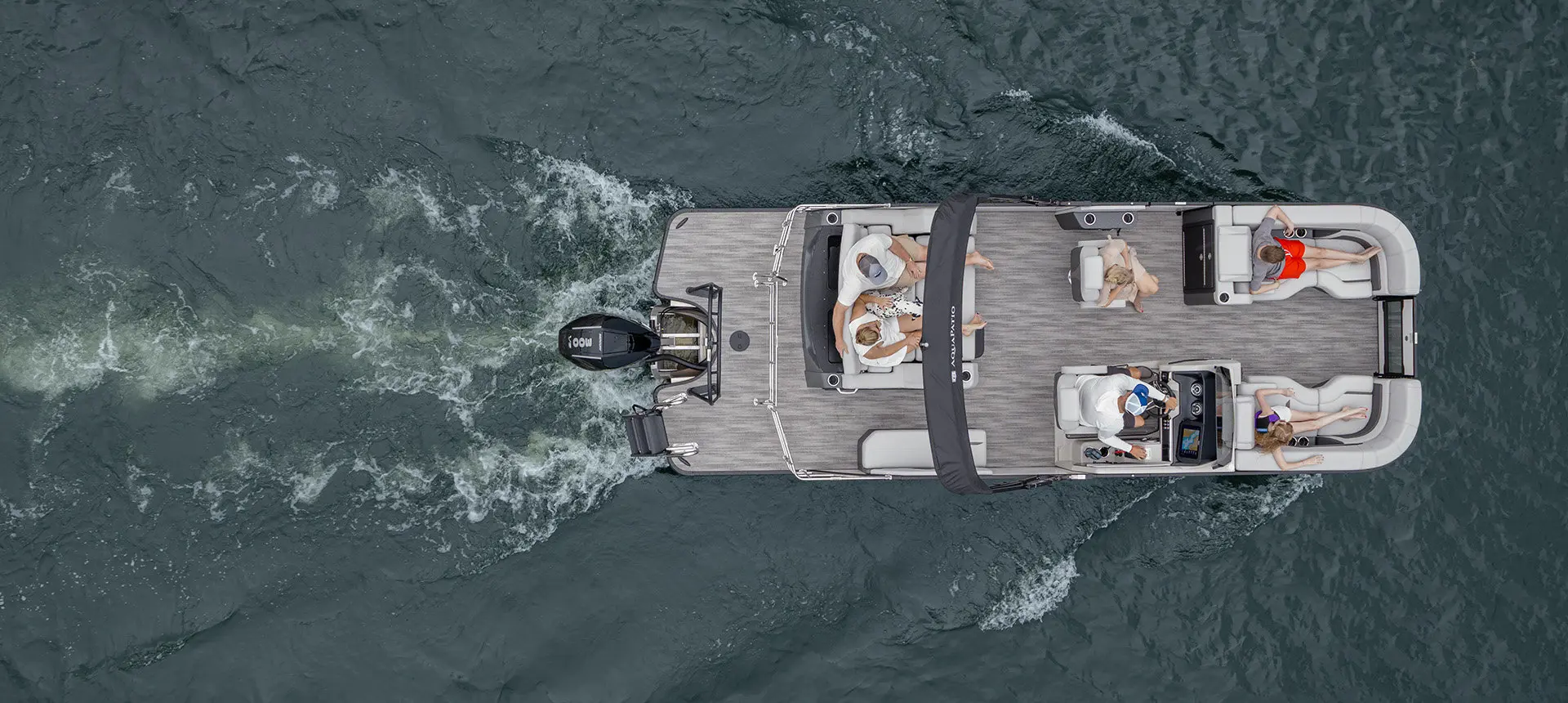 Aerial view of a Godfrey AquaPatio pontoon boat cruising on a lake.