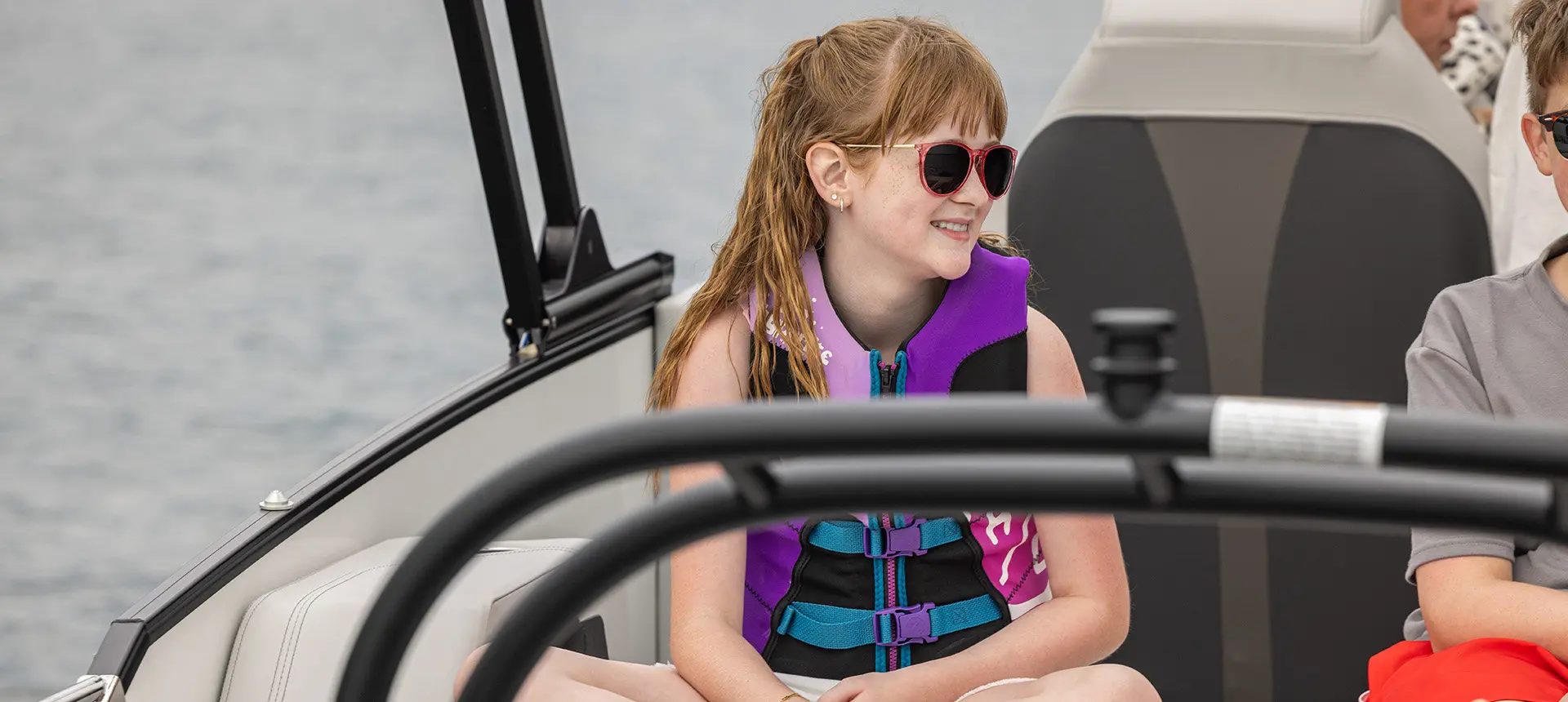 Girl smiling while cruising on a Godfrey AquaPatio pontoon boat.
