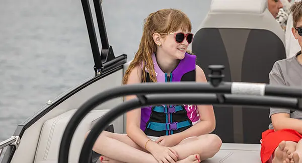Girl smiling while cruising on a Godfrey AquaPatio pontoon boat.