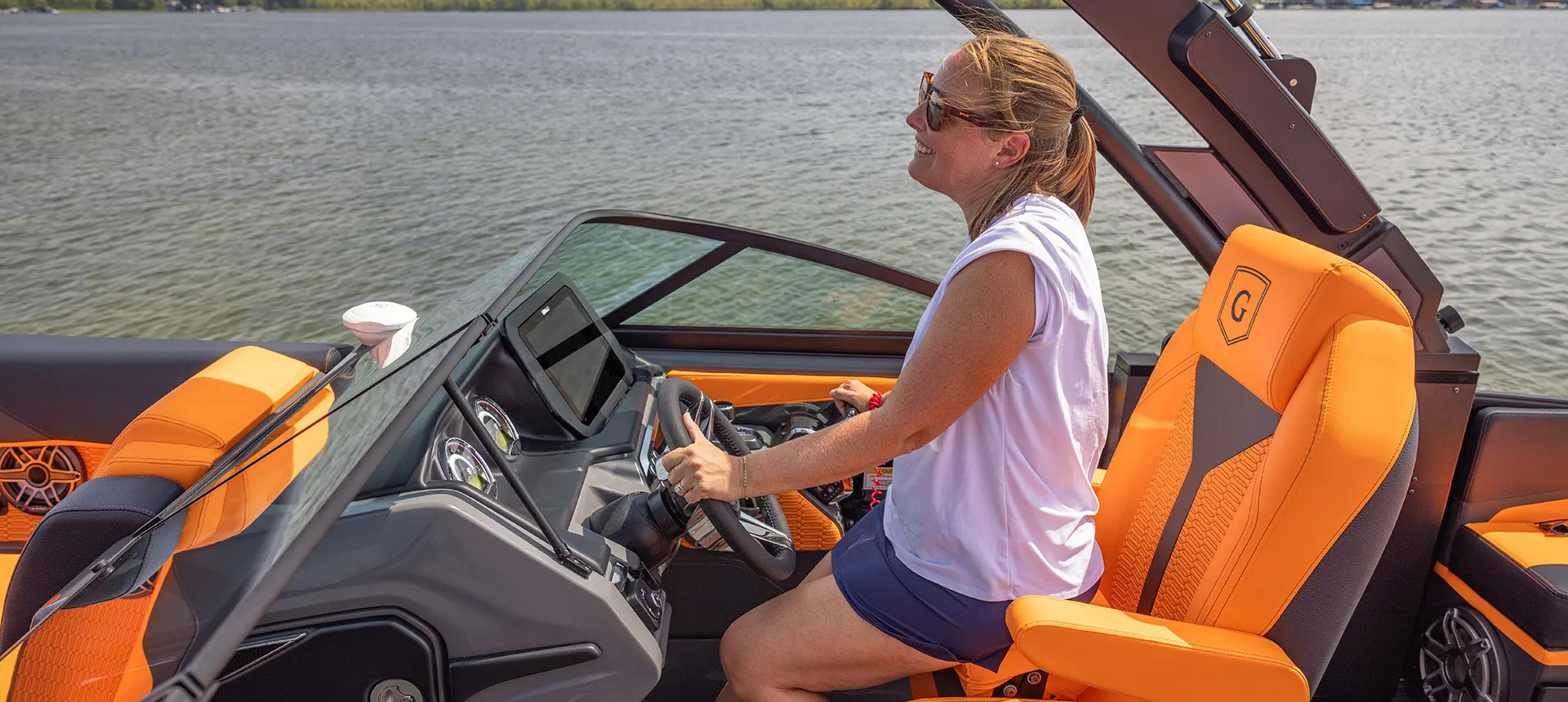 Woman sitting at the helm of a Godfrey AquaPatio pontoon boat.
