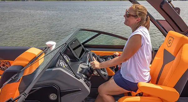Woman sitting at the helm of a Godfrey AquaPatio pontoon boat.