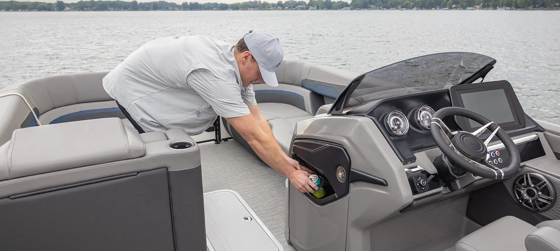 A man using the integrated garbage can on a Godfrey AquaPatio pontoon boat.