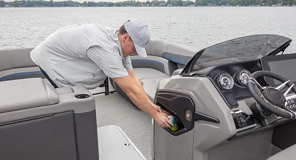 A man using the integrated garbage can on a Godfrey AquaPatio pontoon boat.