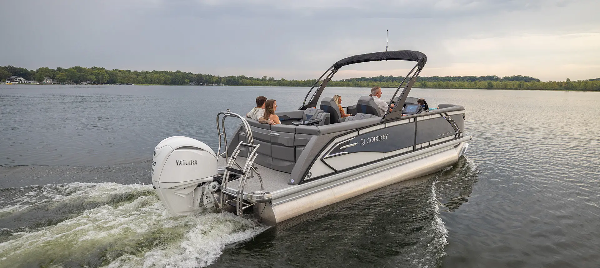 Rear view of a Godfrey AquaPatio pontoon boat cruising on a lake.