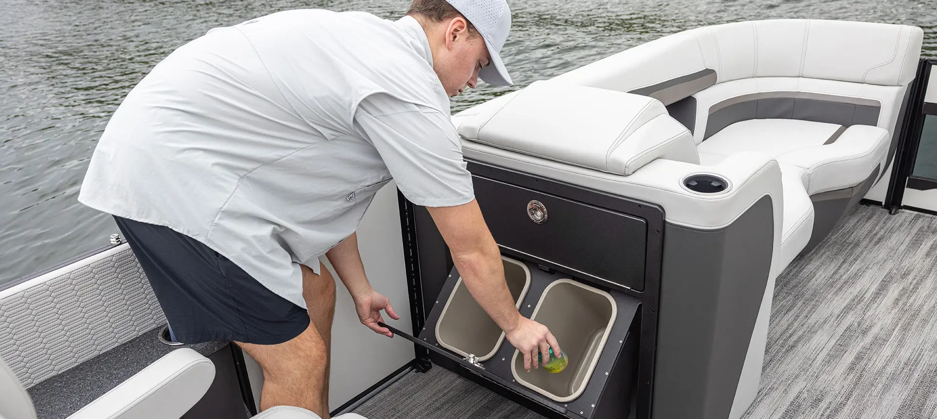 Man using the integrated trash cans on a Godfrey AquaPatio pontoon boat.