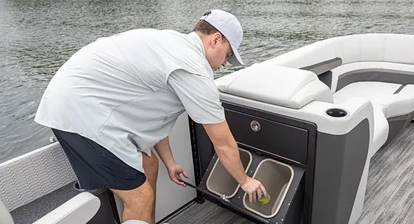 Man using the integrated trash cans on a Godfrey AquaPatio pontoon boat.