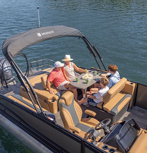 Four people sitting around a table with beverages on a Godfrey Monaco pontoon boat with entertainment layout