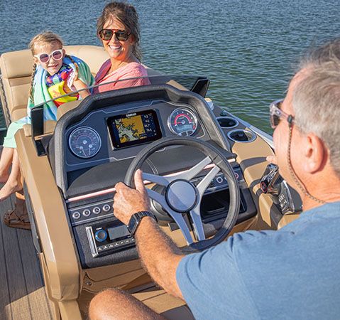 Man sitting at the elevated helm on a Godfrey Monaco pontoon boat. 
