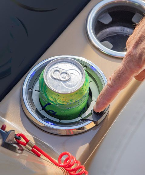 Close-up of a person pressing the heating/cooling button of a cupholder on a Godfrey Monaco pontoon boat