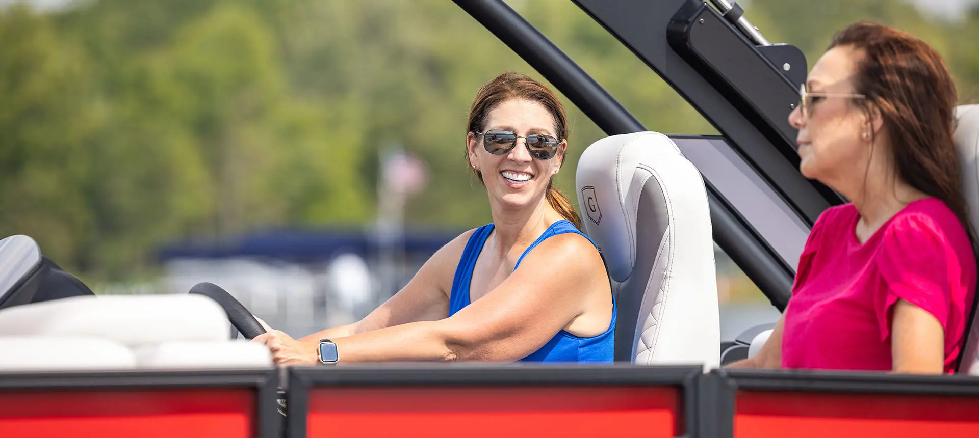 Woman sitting at the helm of a Godfrey Monaco pontoon boat.