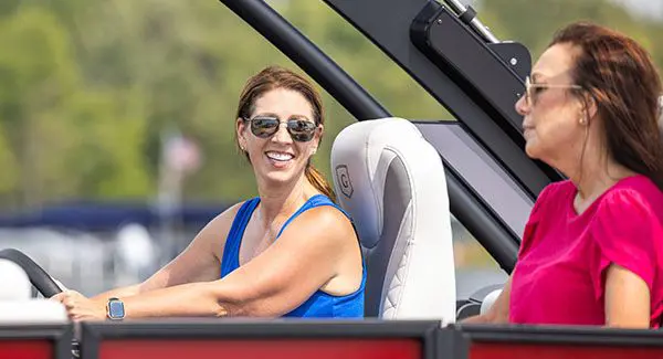 Woman sitting at the helm of a Godfrey Monaco pontoon boat.