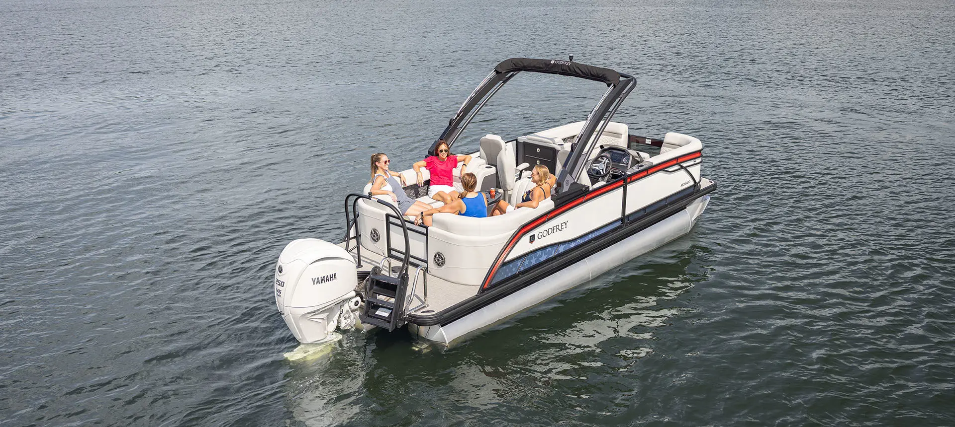4 people sitting on the stern of a Godfrey Monaco pontoon boat.