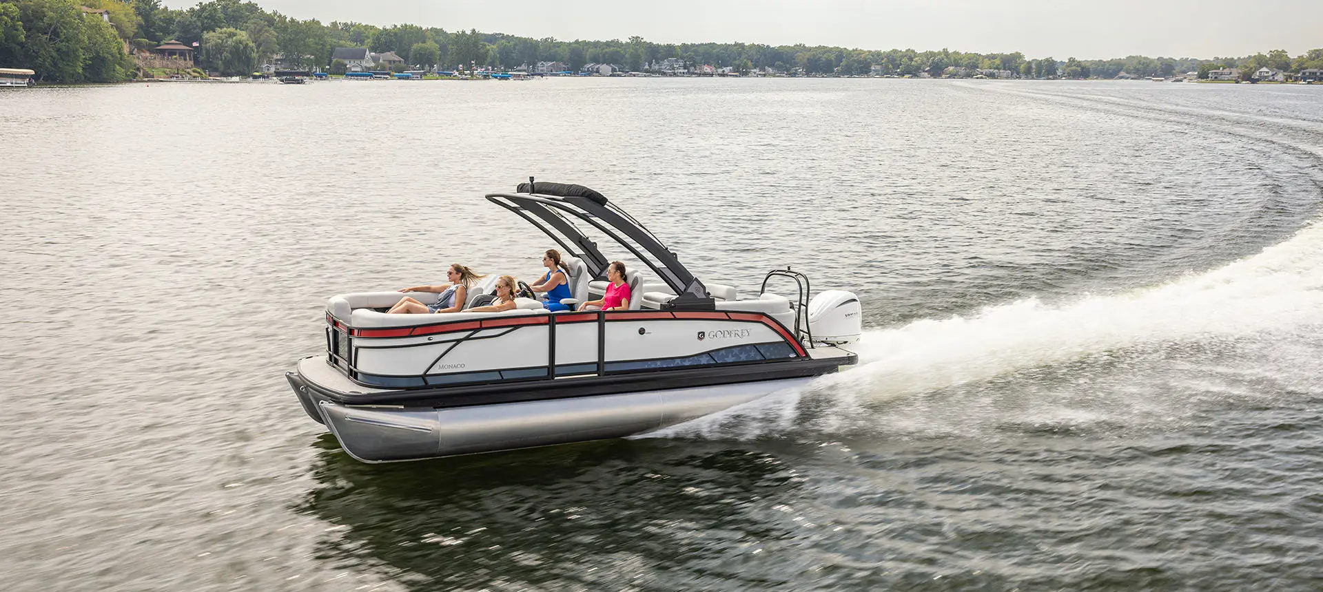 People cruising a lake on a Godfrey Monaco pontoon boat.