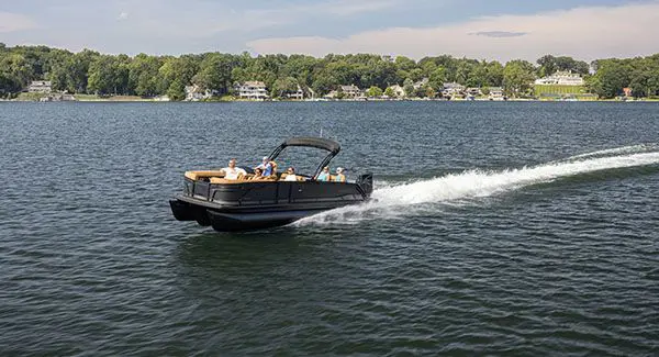 Far away view of a Godfrey Monaco pontoon boat cruising on a lake.
